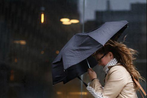 A woman struggles with her umbrella in the wind during a heavy rain storm in New York